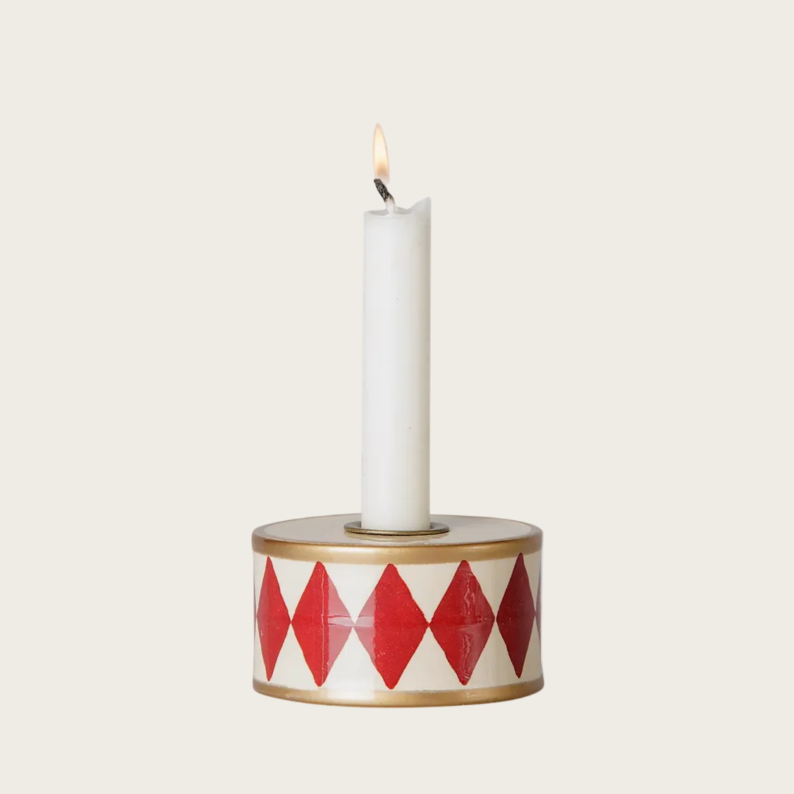 A drum-shaped candle holder designed to look like a white taper candle, featuring a red and white harlequin diamond pattern on the sides and a gold-toned rim. 