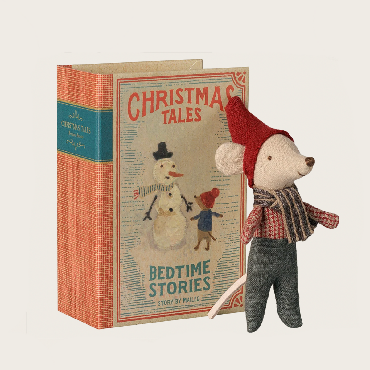 A Christmas-themed mouse baby-in-book set by Maileg. The product includes a large illustrated book titled 'Christmas Tales: Bedtime Stories' with an orange spine and blue front cover, alongside a plush mouse doll wearing a red Santa hat, red plaid scarf, and gray pants.