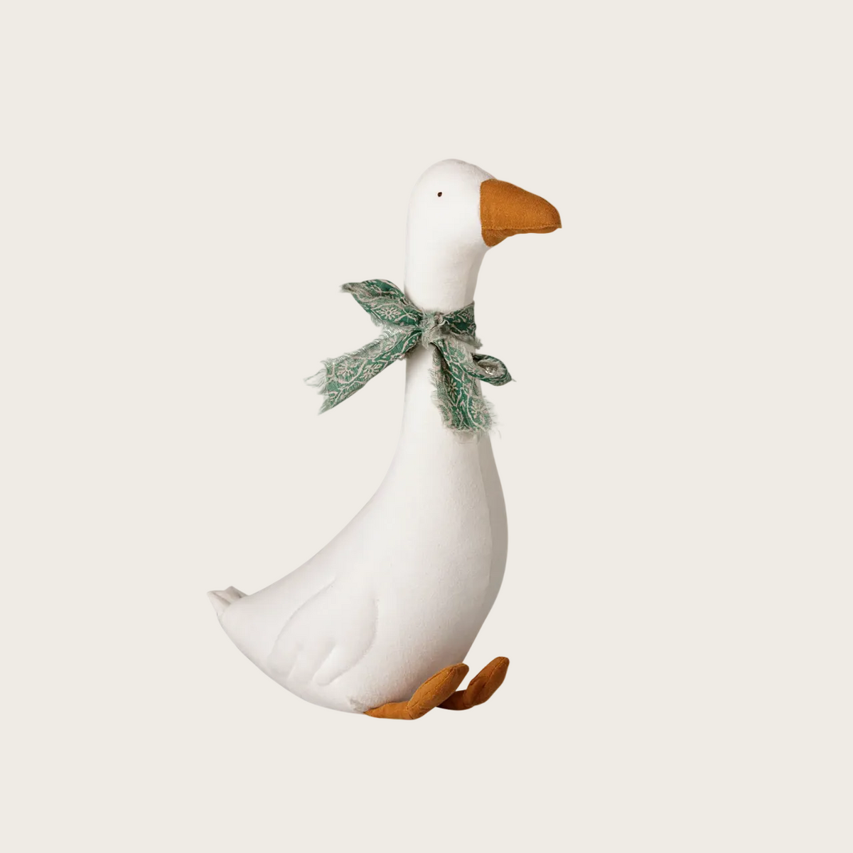A white goose-shaped decorative toy with an orange beak and legs, wearing a green patterned bow. 