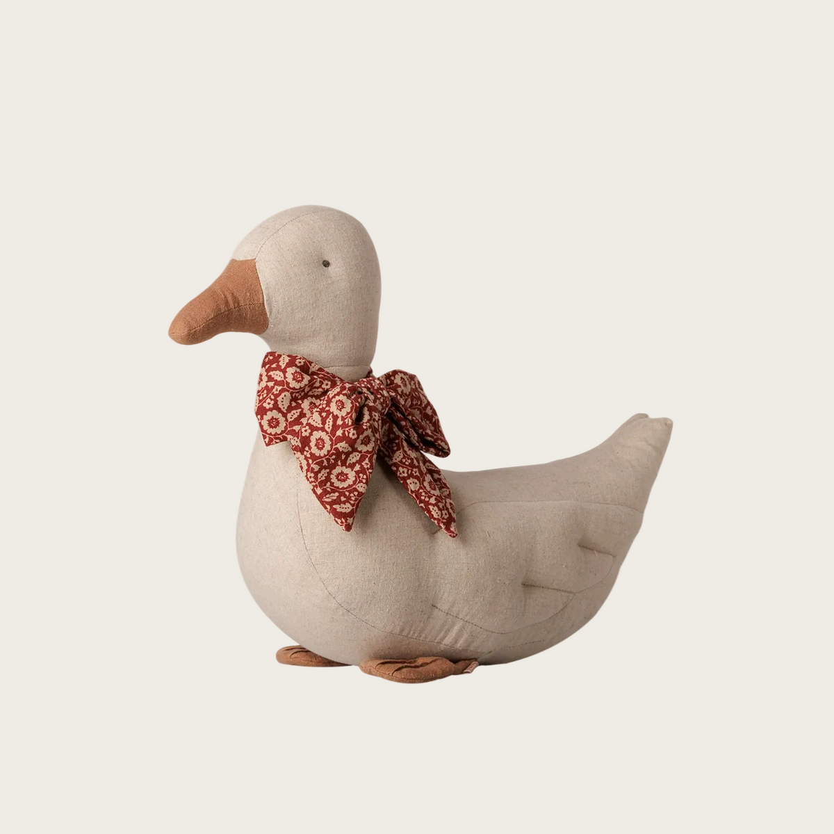 A plush duck toy with a beige body, orange beak and feet, and a red-and-white patterned bow around its neck
