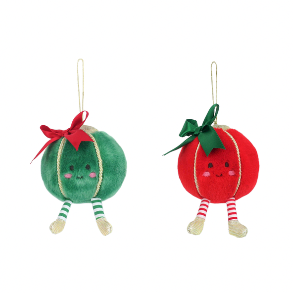 Two round plush Christmas ornaments hanging side by side on a white background. One ornament is green with a red bow and striped green-and-white legs, and the other is red with a green bow and striped red-and-white legs.