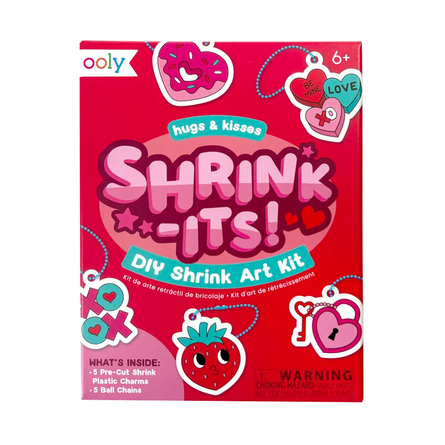 Front of the Ooly Shrink-Its! DIY Shrink Art Kit box, featuring a bright pink background with colorful heart-shaped charms, a strawberry illustration, and product details including age 6+ and what's inside.