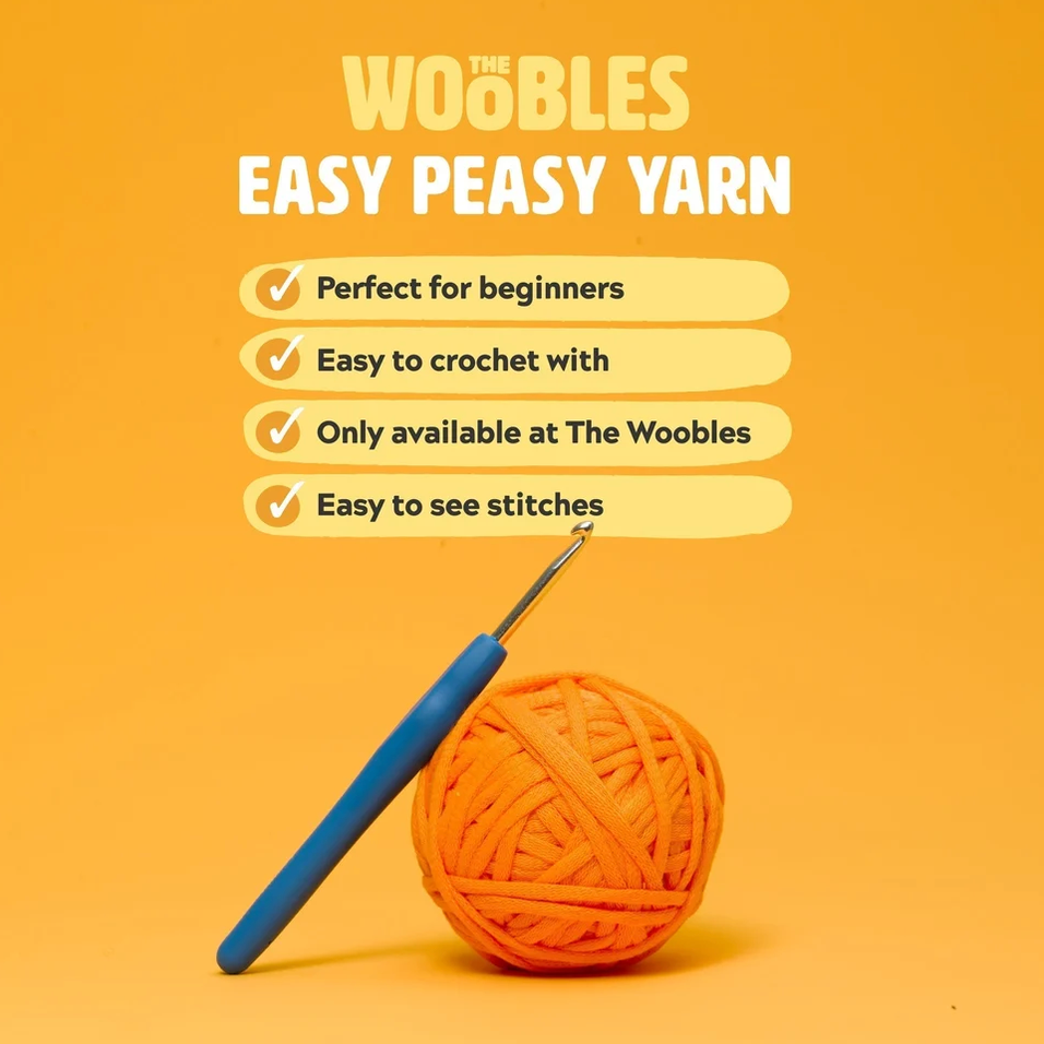 Promotional graphic for 'The Woobles Easy Peasy Yarn' featuring a bright orange ball of yarn and a blue-handled crochet hook on a solid orange background, with text listing product benefits.