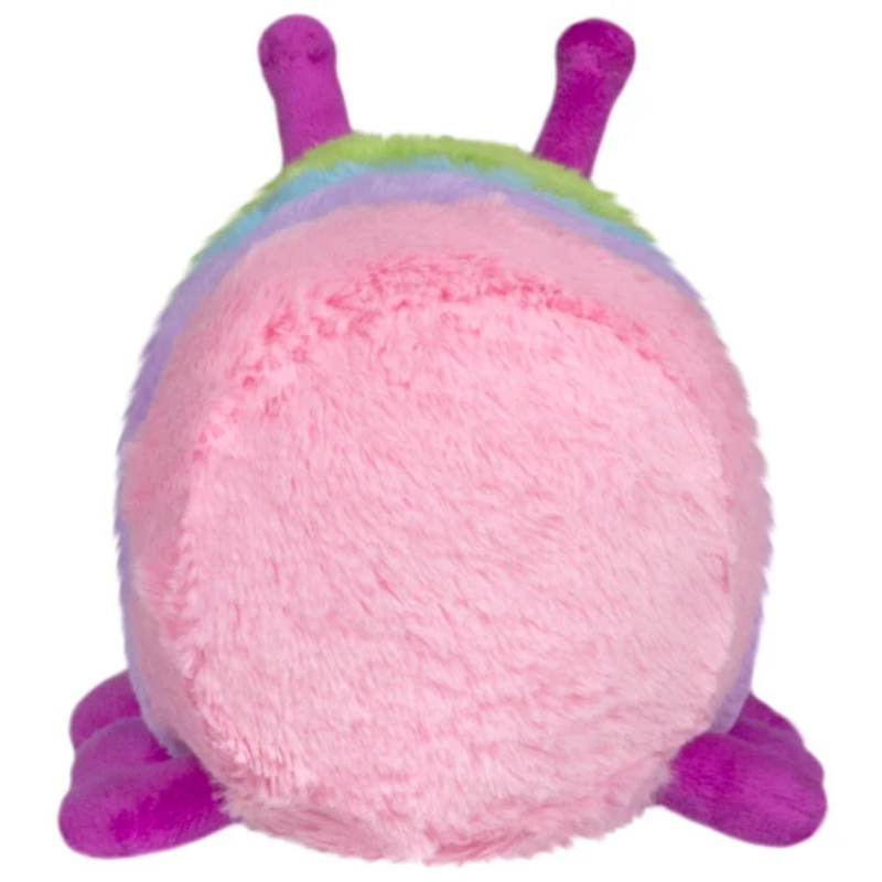 A pink plush toy with purple feet and antennae, and a rainbow-colored stripe around its neck, shown against a plain white background.
