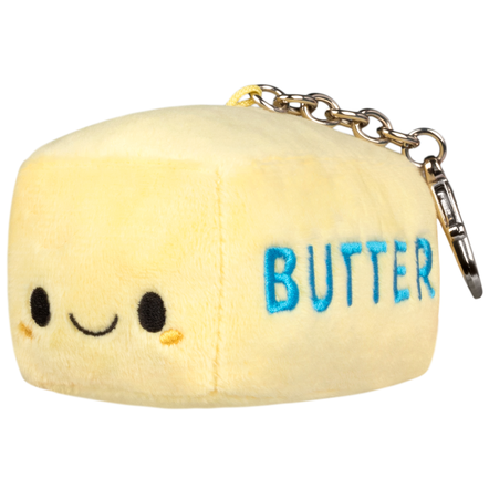 A plush keychain shaped like a butter cube in pale yellow, with embroidered black eyes and smile, blue 'BUTTER' text, and a gold-tone chain clasp on a white background.