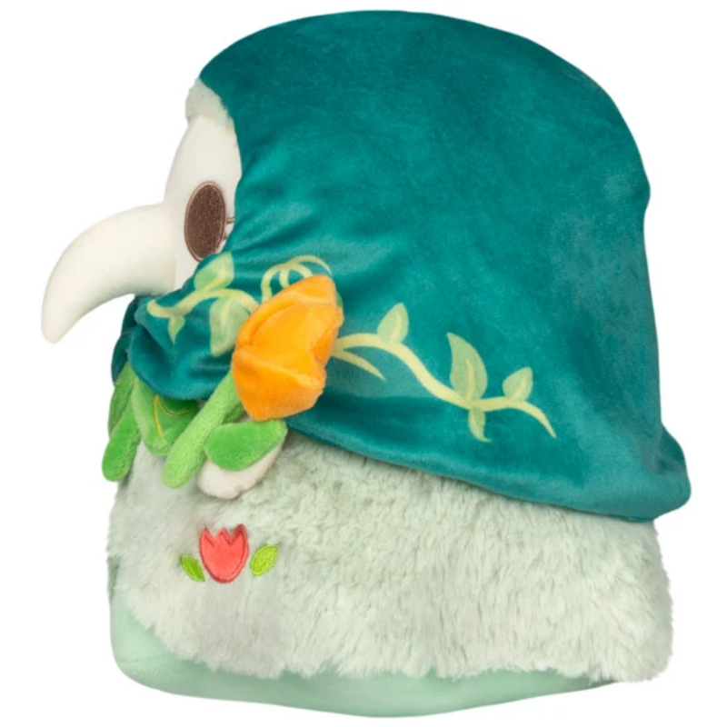 A plush bird character hat or headpiece featuring a teal velvet crown, white fluffy body, green vine details, and an orange flower accent, shown on a plain white background.