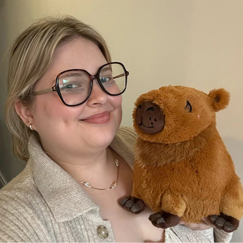 Person holding a plush bear toy against a plain background