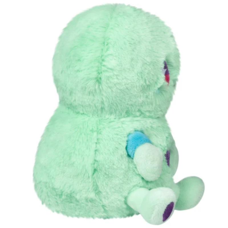 A mint green plush toy with a fuzzy texture, featuring small blue and purple accents on its limbs and a small red detail on its side, shown against a plain white background.