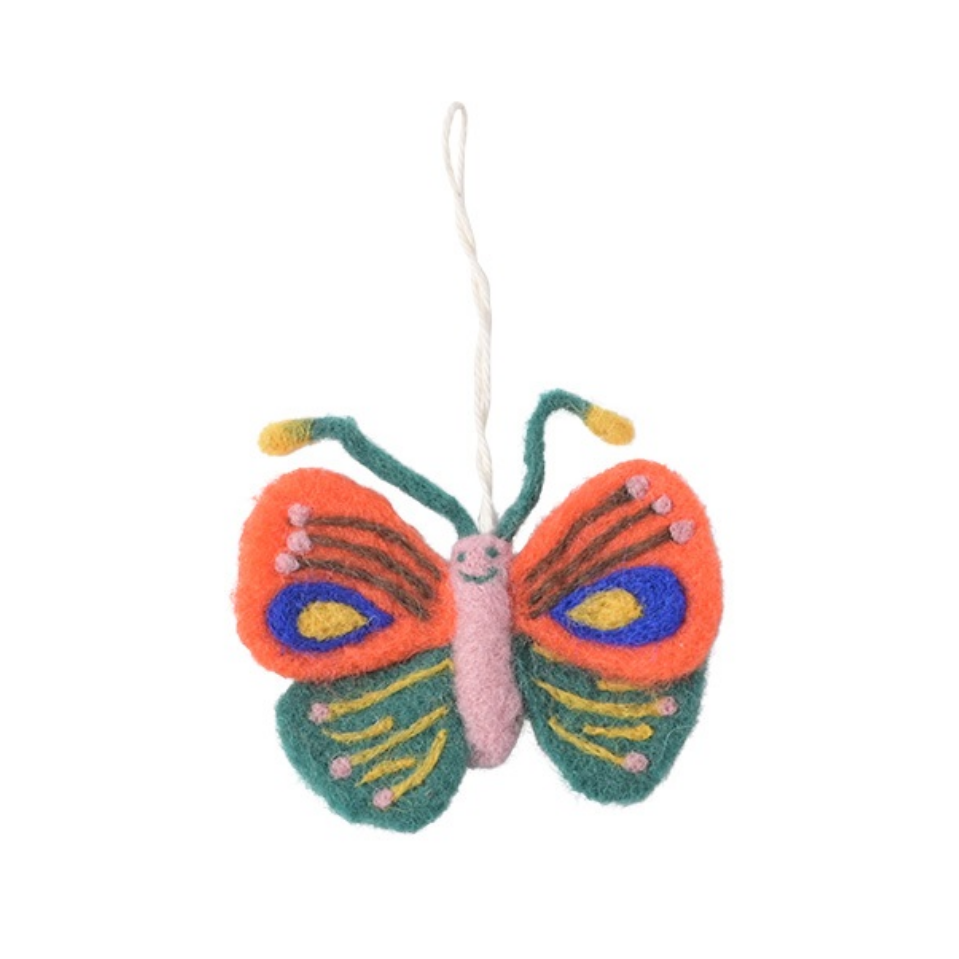A handcrafted felt butterfly ornament with orange wings, green wings, a pink body, and yellow and blue accents, hanging by a thin white string against a plain white background.