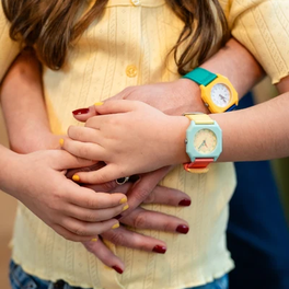 Two children wearing colorful watches, one with a yellow watch and the other with a blue watch.
