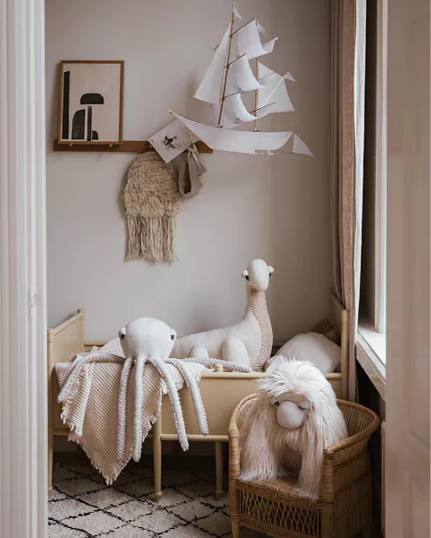Nursery room with wooden crib, plush toys, and decorative elements.