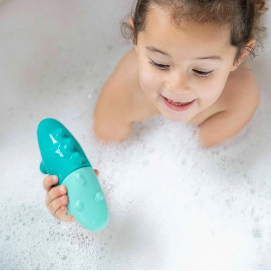 Child playing with a teal bath toy in bubbles