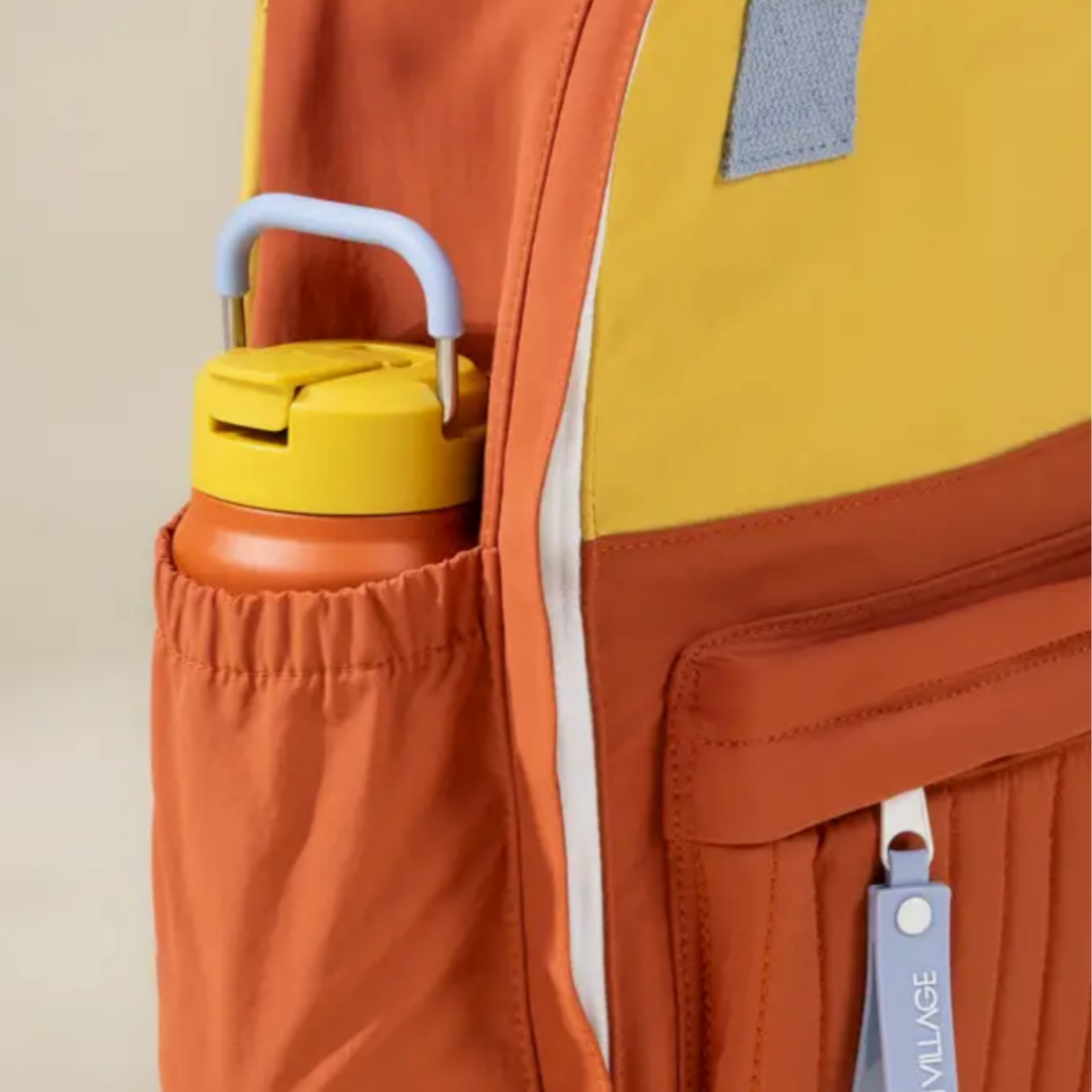 Orange backpack with a yellow water bottle in a pocket on a beige background