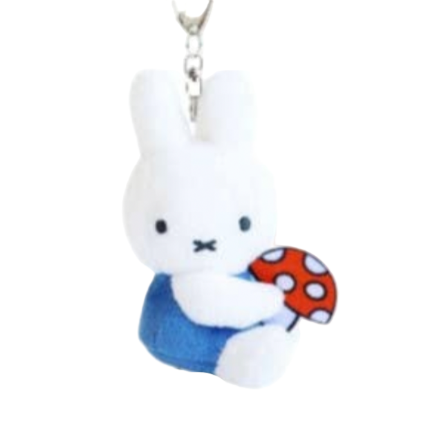 Plush keychain of a white rabbit holding a red mushroom on a white background