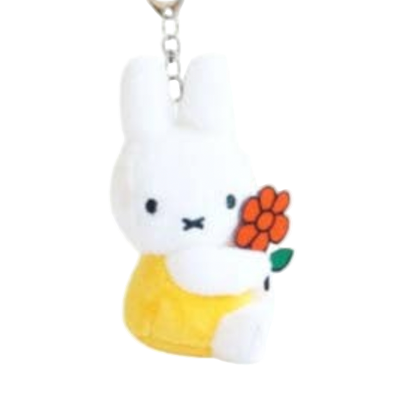 Plush keychain of a white rabbit with a yellow dress and orange flower on a white background
