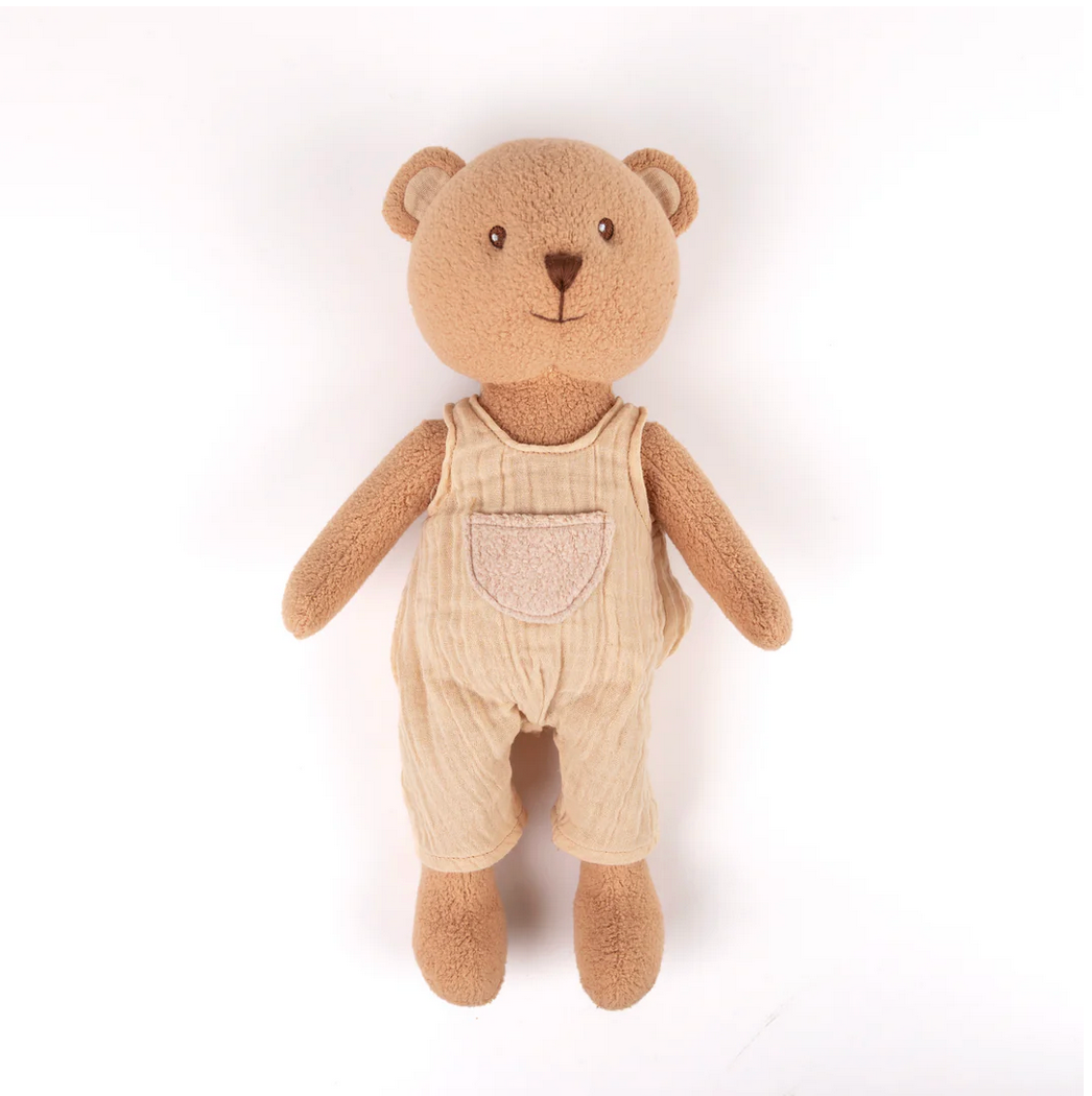 Teddy bear wearing beige overalls on a white background