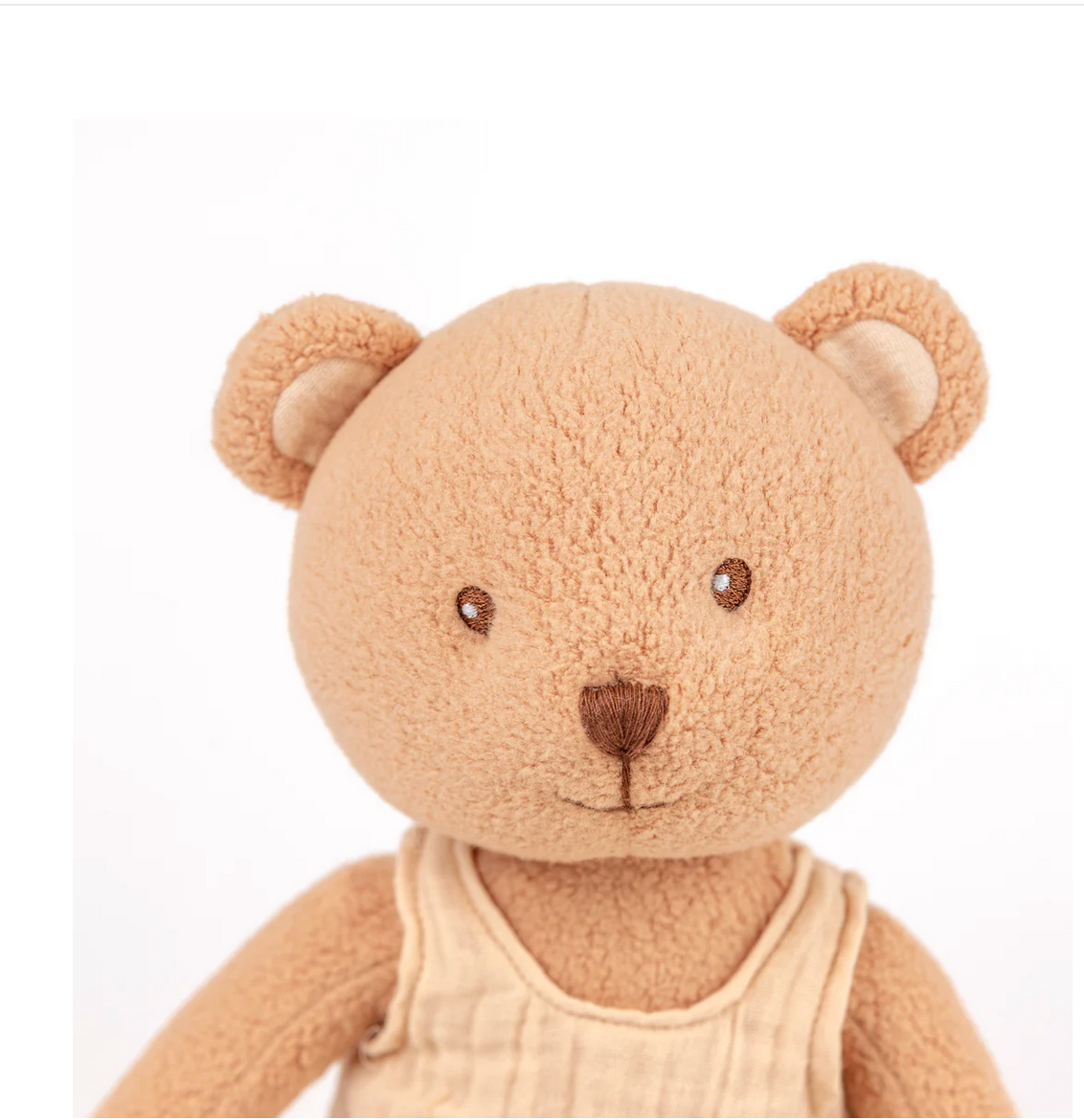Brown teddy bear with a cream outfit on a white background