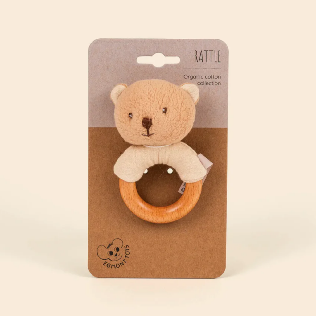 Baby rattle with bear design on a cardboard packaging against a beige background