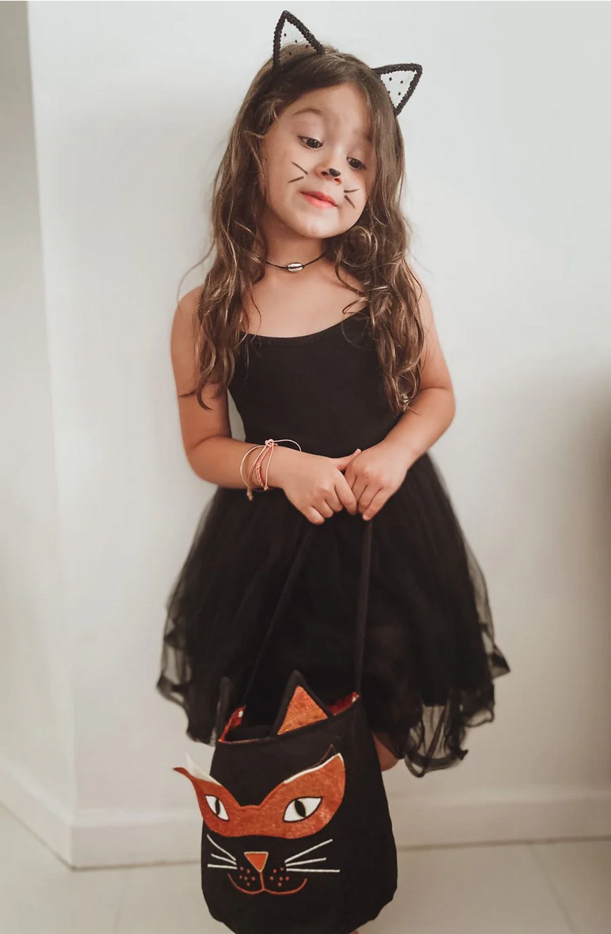 Child wearing a black dress with cat ears and a matching bag on a white background