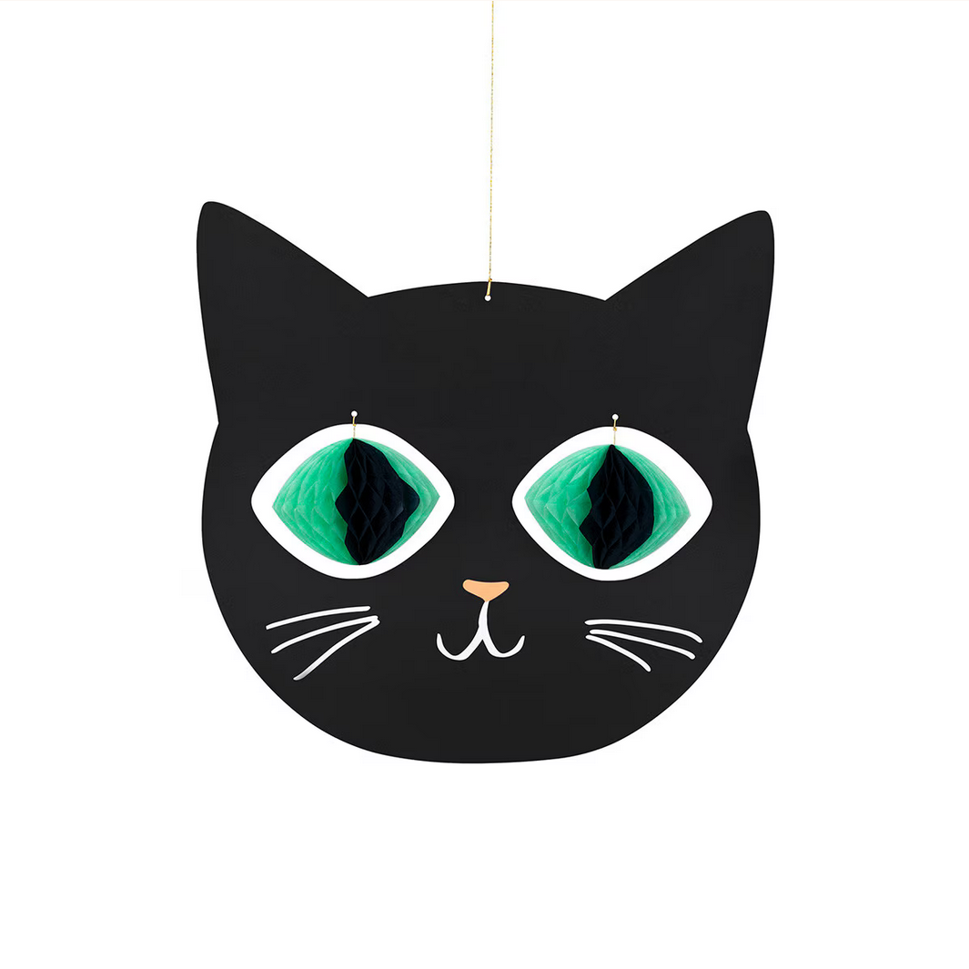 Black cat-shaped decoration with green eyes on a white background
