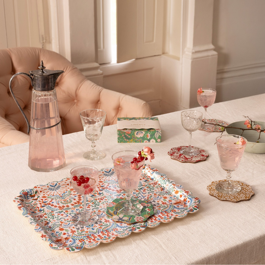 Table setting with floral platter, glasses, and decorative items in a cozy room.