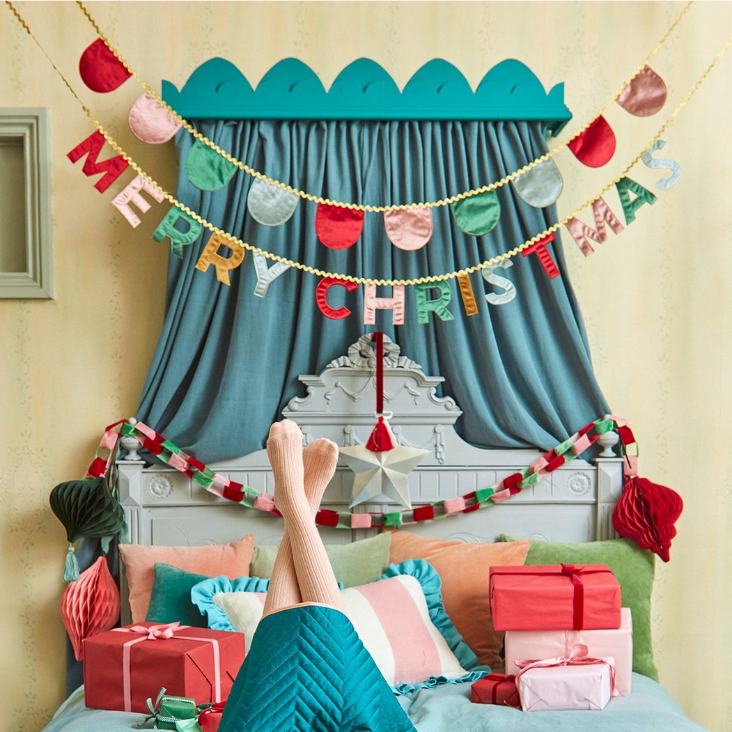 Decorated room with Christmas decorations, including a 'Merry Christmas' banner and presents.