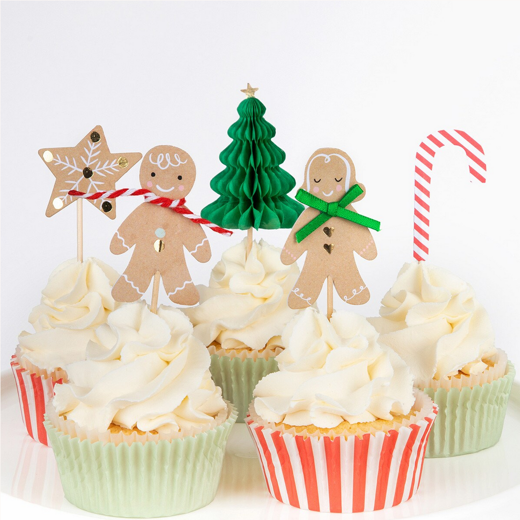 Decorative Christmas-themed cupcake toppers on cupcakes with white frosting.