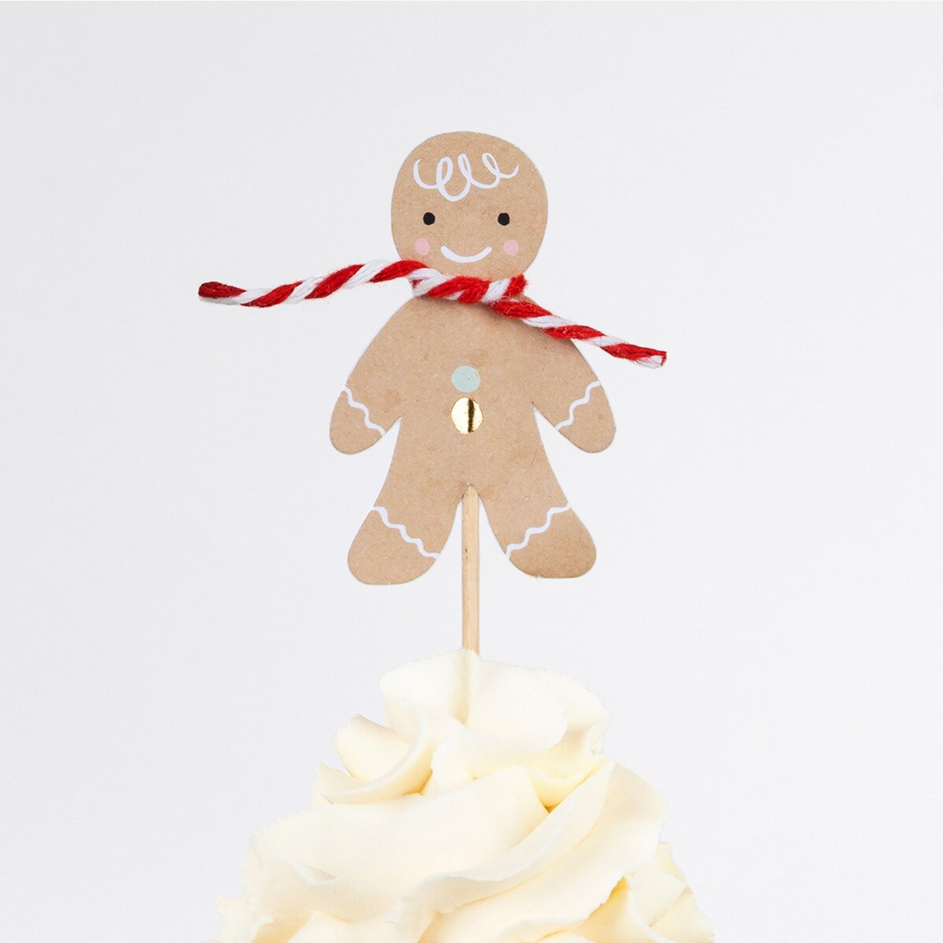 Gingerbread man cake topper with a candy cane on a white background