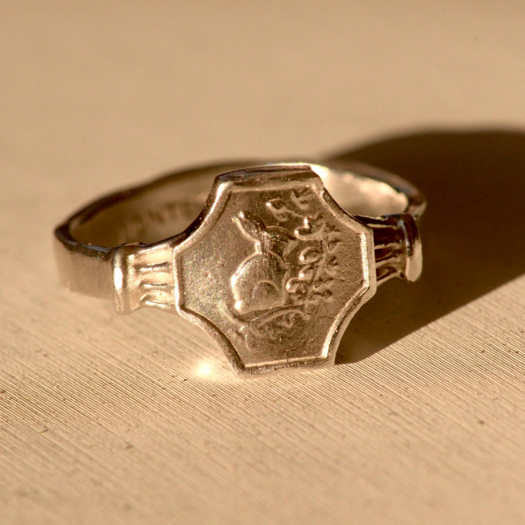 Silve ring with engraved design on a beige surface