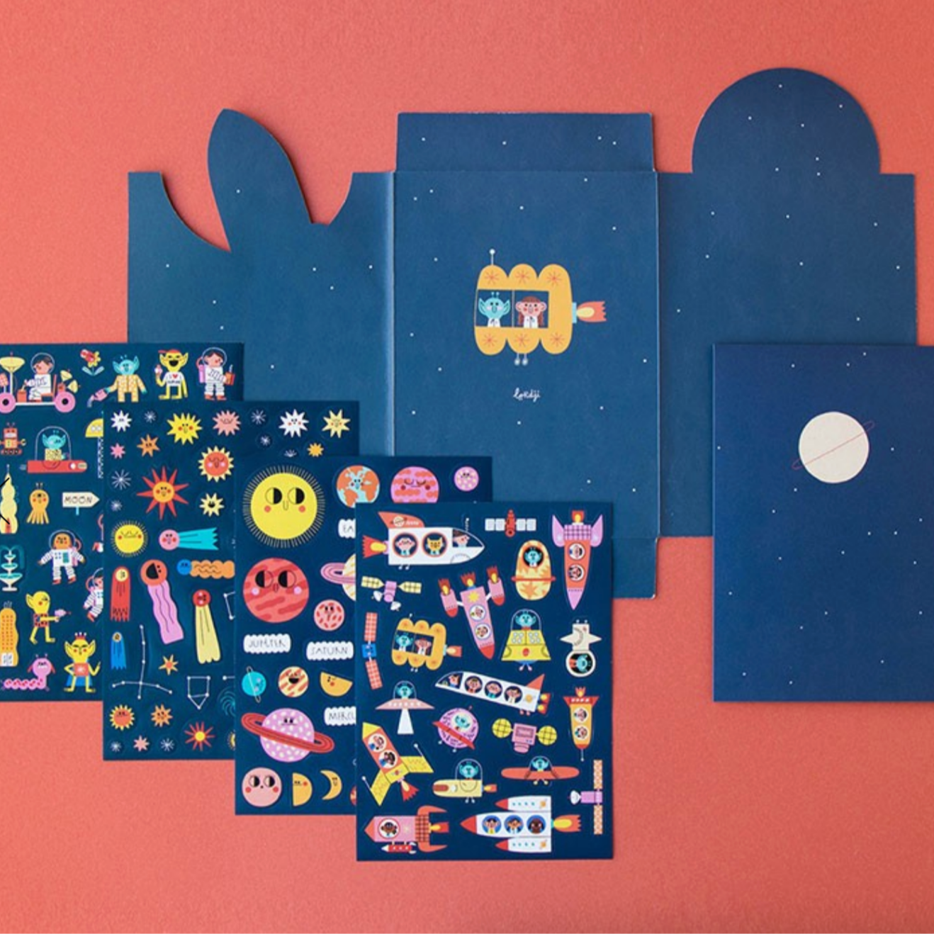 Set of blue and dark blue notebooks with colorful illustrations on a pink background