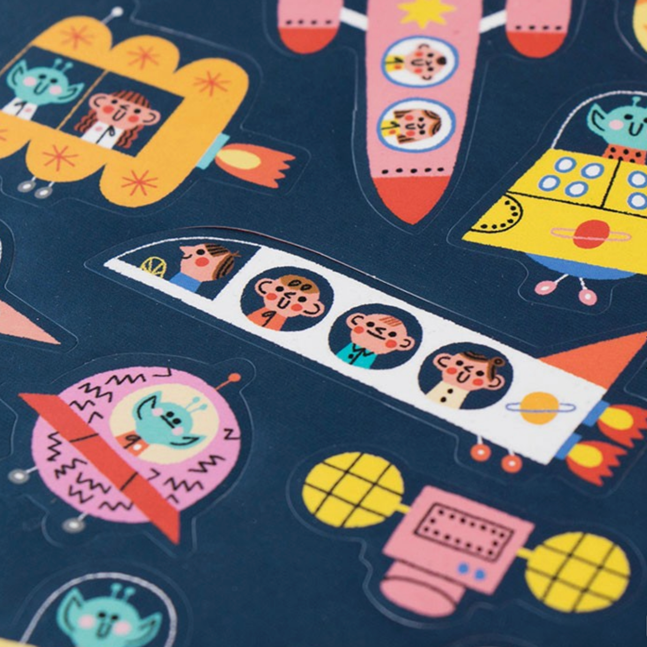 Colorful space-themed stickers with rockets and alien faces on a dark blue background.