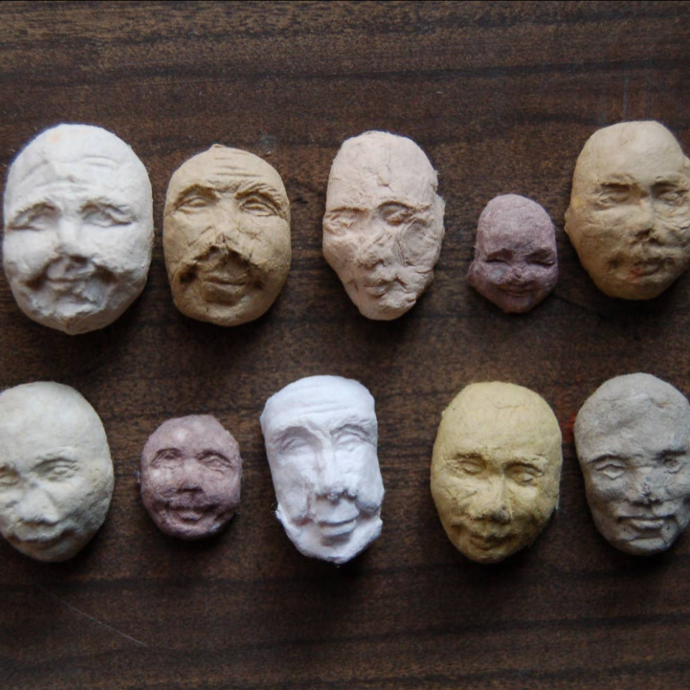 Row of ceramic face sculptures on a wooden surface