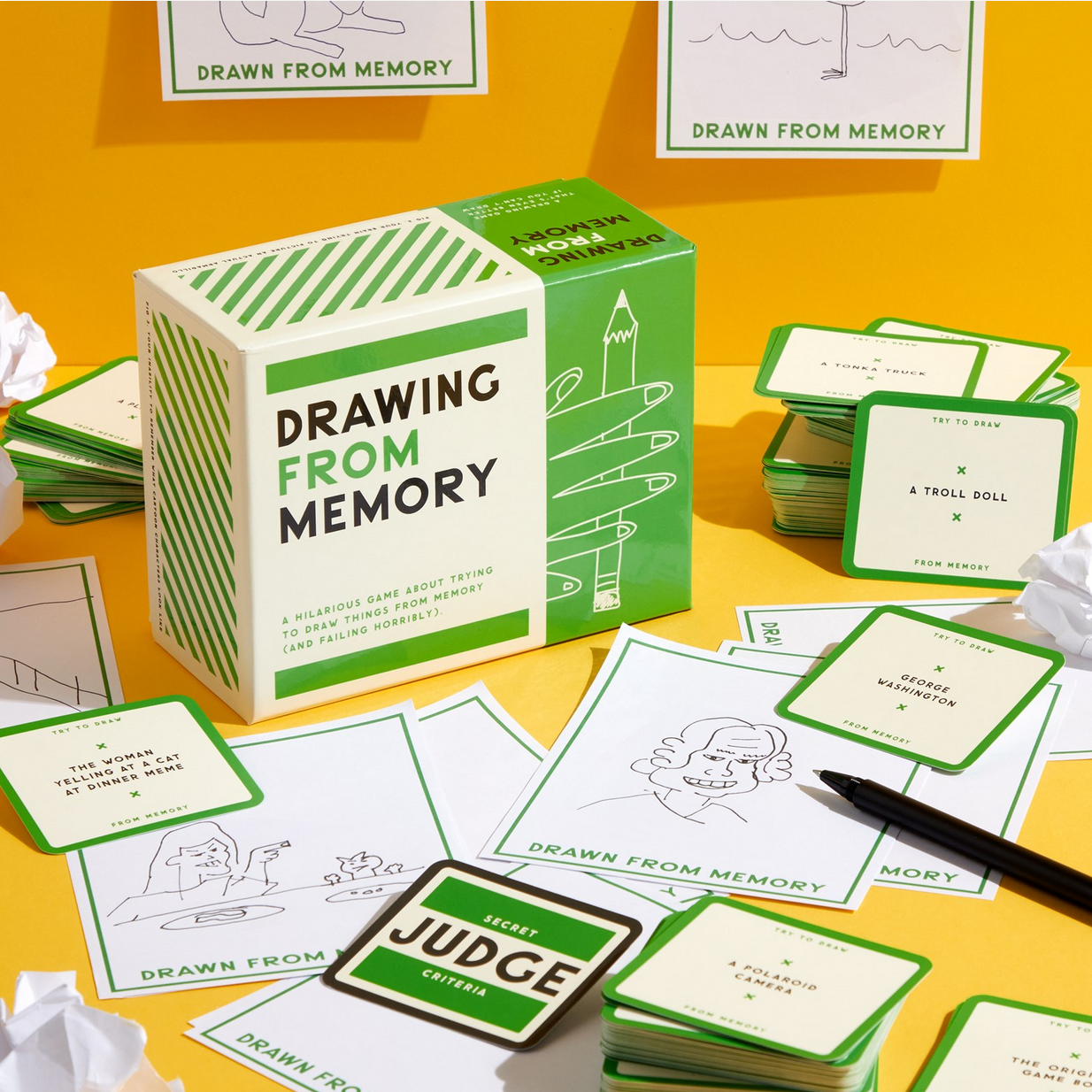 Card game 'Drawing from Memory' with cards and box on a yellow surface