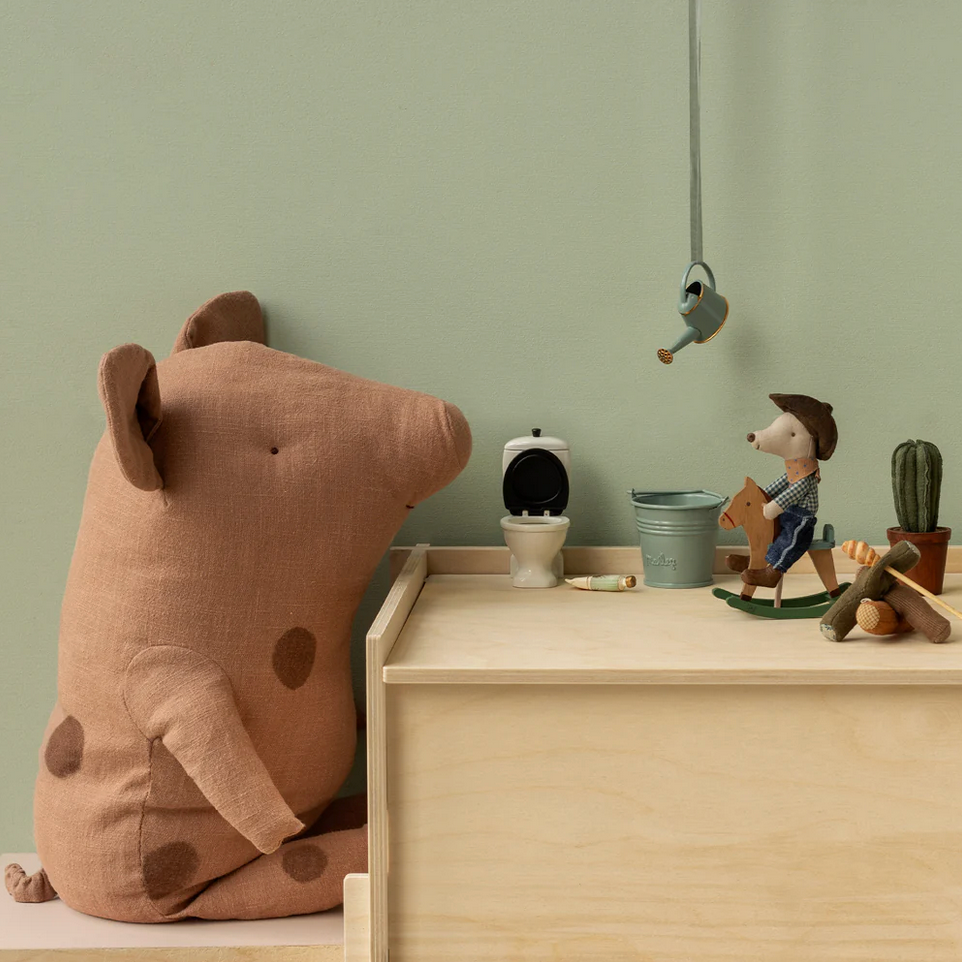 Children's room with a large brown plush toy, small figurines, and a green wall.