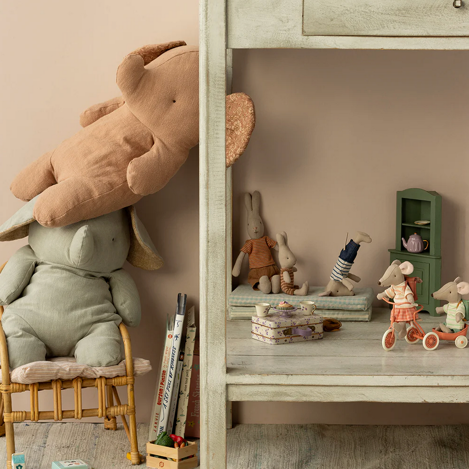 Children's toys including a large teddy bear, elephant, and mouse on shelves in a room.