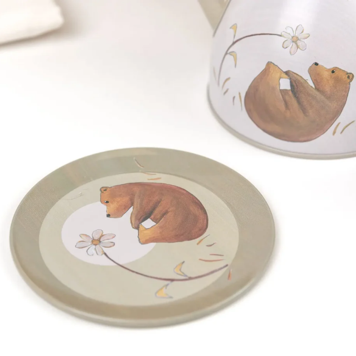 A metal coaster with bear illustration on a white surface
