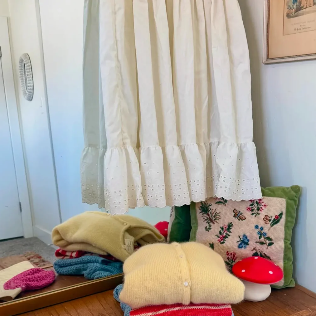 Stack of folded clothes on a wooden surface with decorative items in the background