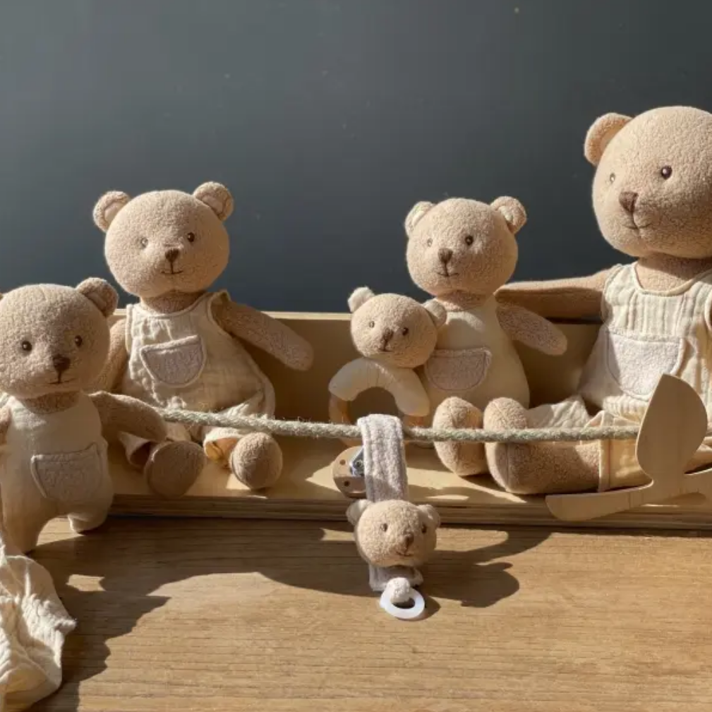 Set of teddy bears in a wooden toy boat on a wooden surface with a dark background