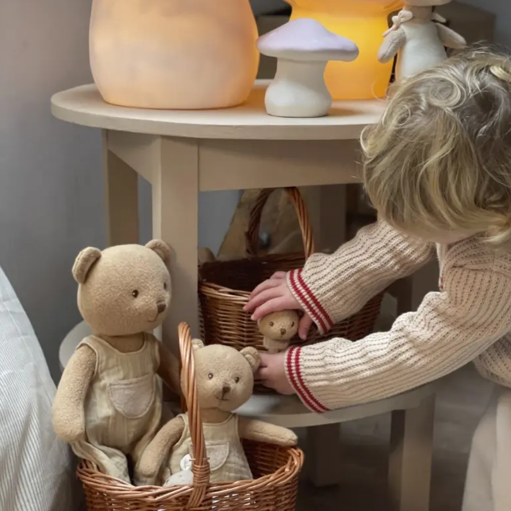 Child playing with teddy bears near a table with mushroom-shaped lamps.