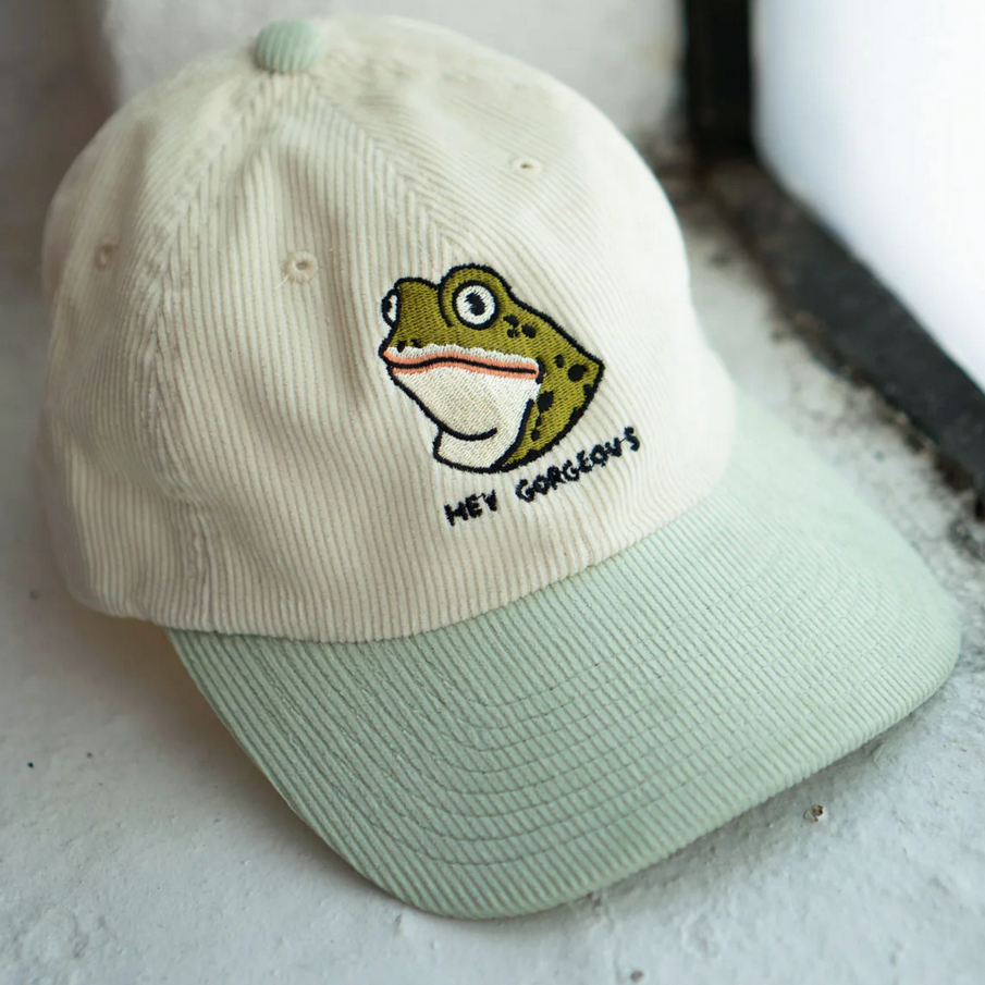 Cap with a frog design and text on a textured surface