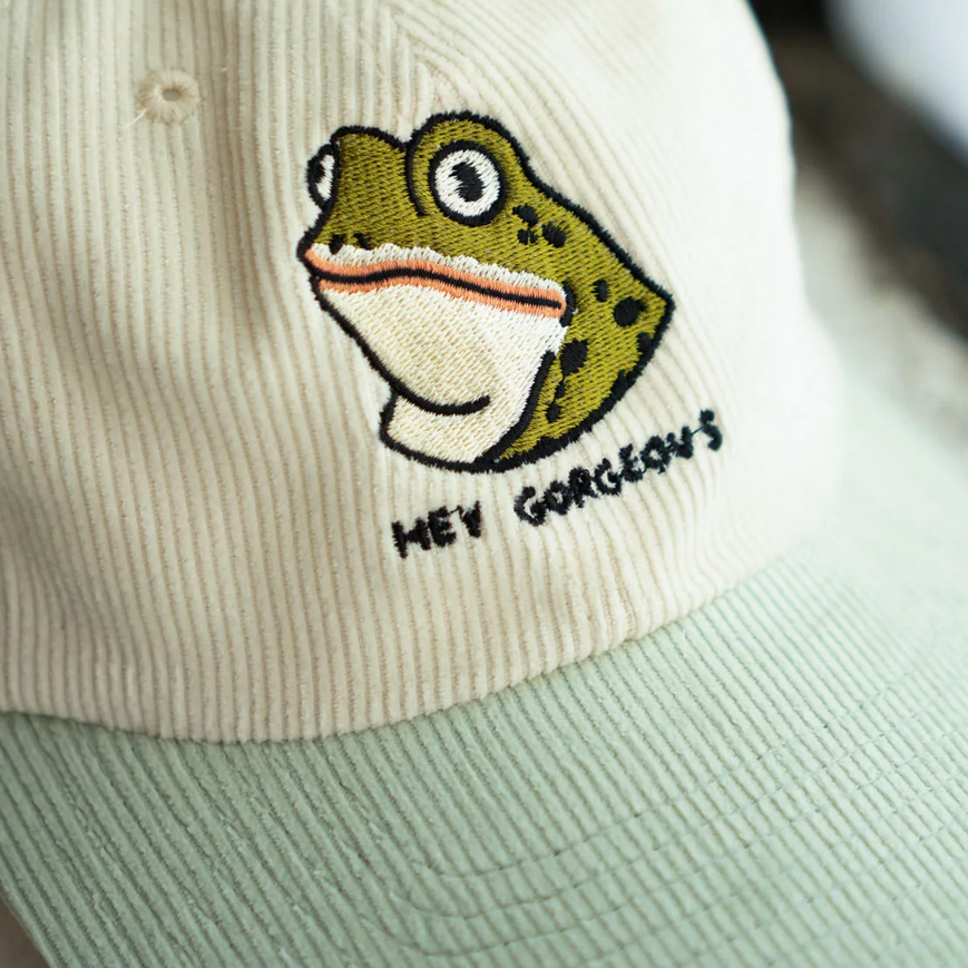 Cap with a frog design and text 'Hey Gorgeous' on a light background
