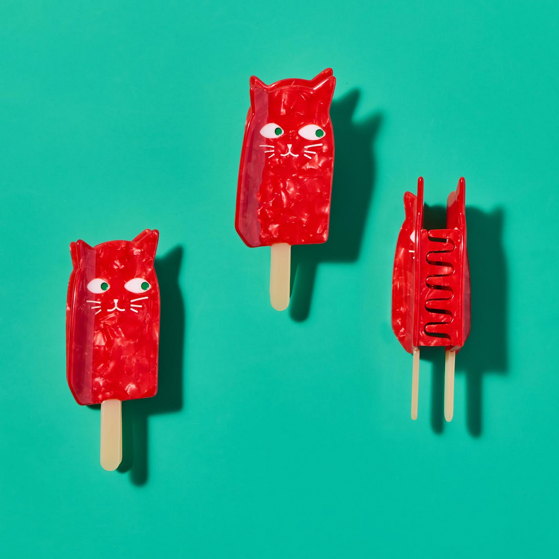 Three red cat-shaped popsicles on a teal background