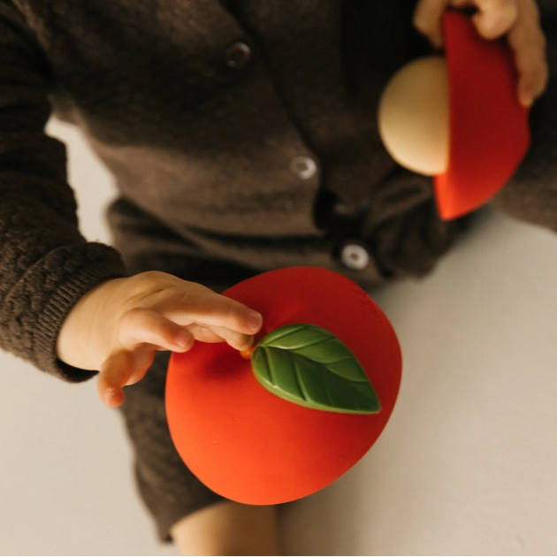 Person holding a red felt apple with a green leaf against a neutral background