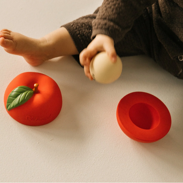 Child playing with colorful fruit-shaped toys on a light surface