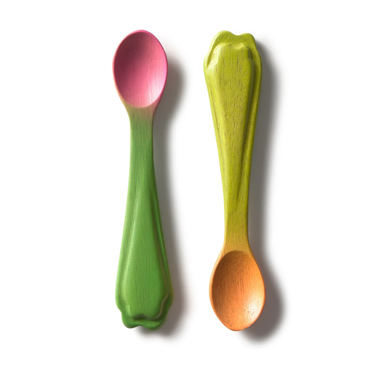 Two wooden spoons with green and pink handles and orange body on a white background