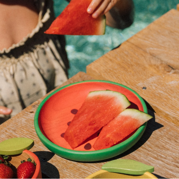 Watermelon slices on a green plate with a person in the background