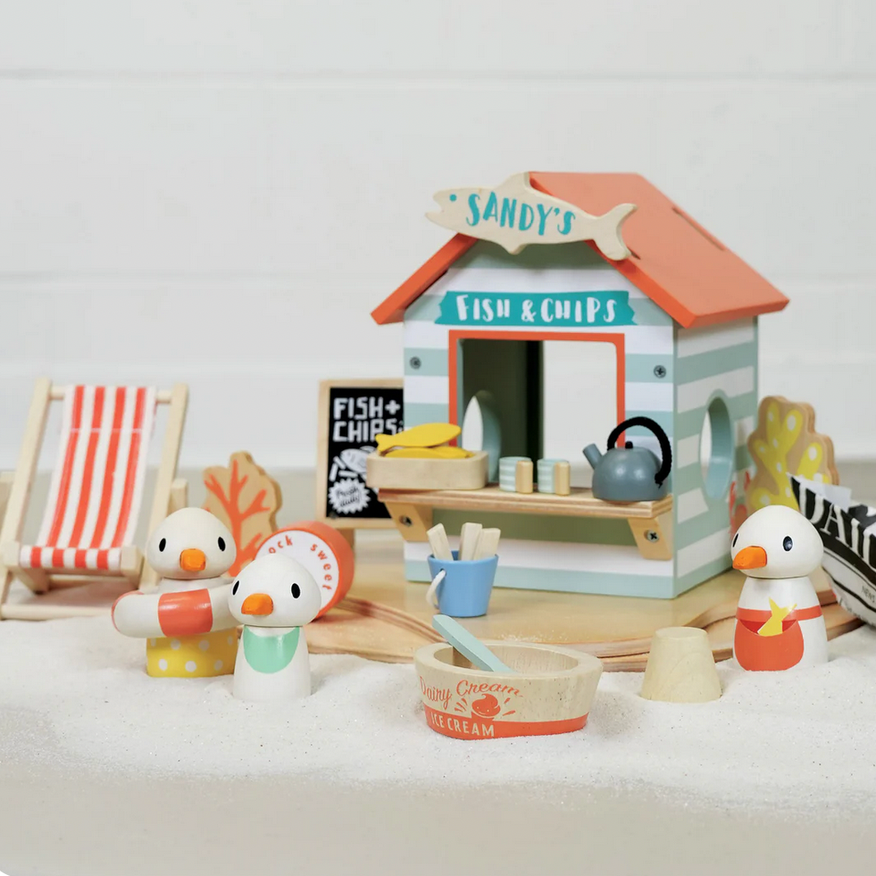 Toy fish and chip shop set with wooden ducks on a white surface
