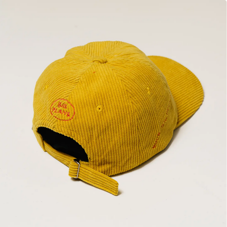 Yellow corduroy cap with a brand logo on a light gray background
