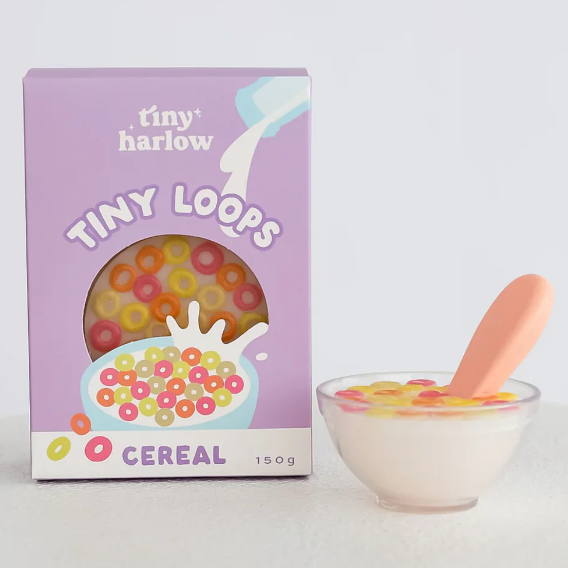 Box of 'Tiny Loops' cereal with a bowl of cereal and spoon on a light gray background