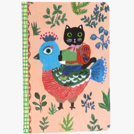 Notebook with a colorful design of a cat riding a bird on a peach background with green leaves.